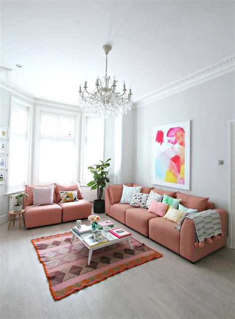 A Living Room Filled With Pink Couches And A Chandelier Hanging From