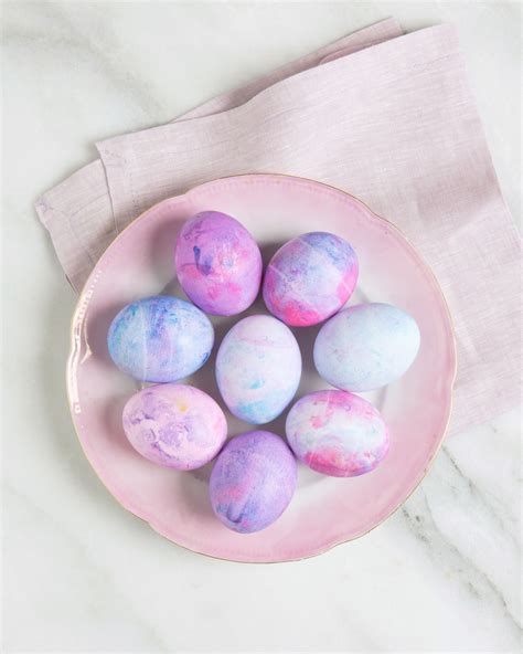 A Pink Bowl Filled With Dyed Eggs On Top Of A White Marble Countertop