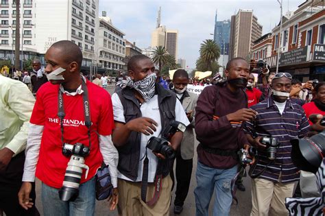 a group of photographers march down the streets of nairobi with their mouths taped up as a sign