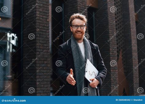 Giving Hand To Shake Stylish Man With Beard And In Glasses Is Outdoors Near Building Stock