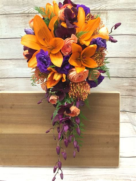 Cascading wedding bouquet of fuchsia phalanopsis orchids, white cymbidium orchids with a pink throat and white dendrobium orchids. Orange Lily purple lisianthus coral peach ranunculus ...