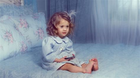 Nettes kleines Mädchen sitzt auf dem Bett das blaues Kleid nette HD