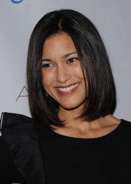 A Smiling Woman With Dark Hair Wearing A Black Top