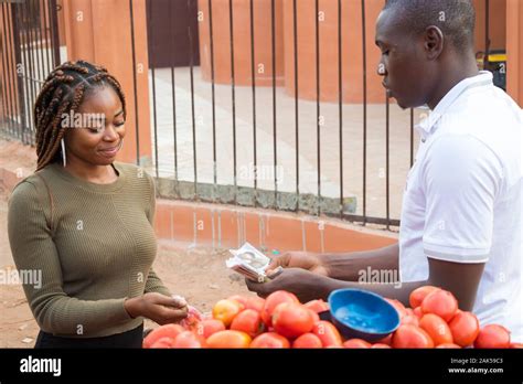 Young African Woman Selling Tomatoes In A Local African Market To A