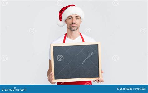 Positive Mature Man In Santa Claus Hat And Apron Hold Blackboard With