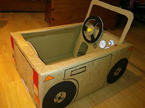 A Cardboard Box Shaped Like A Car With Wheels And Steering Wheel On The Inside Sitting On A
