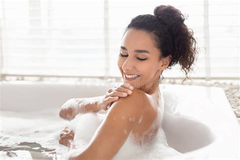 Lovely Millennial Woman Lying In Bathtub With Foam Enjoying Bubble Bath Touching Soft Silky