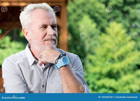 Confident Senior Man Smiling And Thoughtfully Touching His Chin Stock