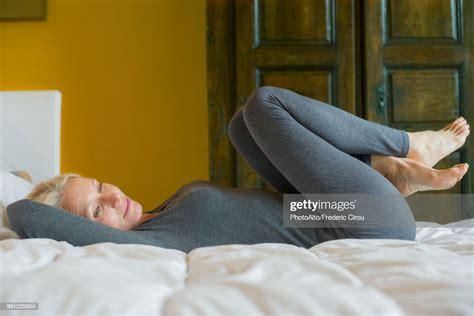 Mature Woman Lying On Bed With Knees To Chest Photo Getty Images