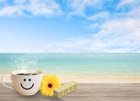 Cup Of Coffee With Happy Face On Sand Beach Over Blue Sky Stock Photo