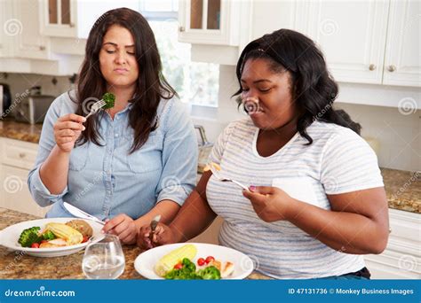 Two Overweight Women On Diet Eating Healthy Meal In Kitchen Stock Photo