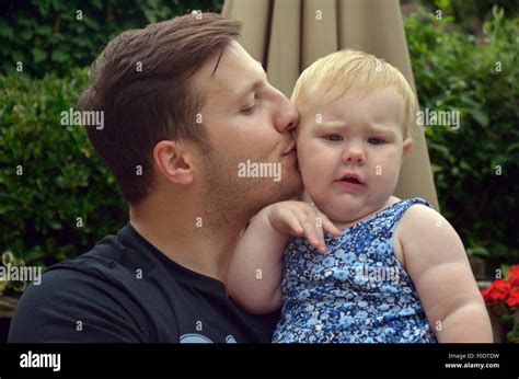 A Young Father Affectionately Kissing His Ten Month Old Daughter Stock