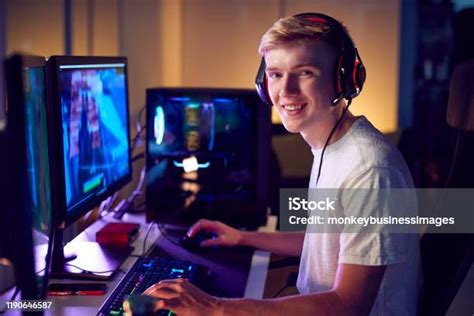 Portrait Of Teenage Boy Wearing Headset Gaming At Home Using Dual