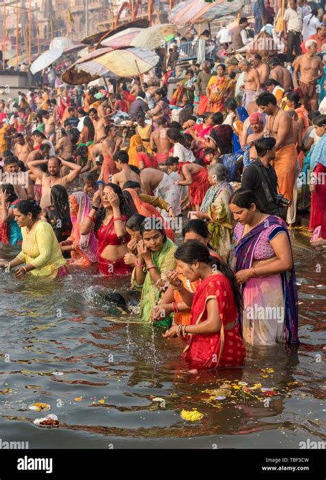hindu believers bath and perform ritual bath and puja prayers at ghats in the river ganges