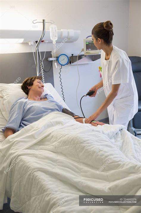 Female Nurse Checking Patient Blood Pressure On Hospital Bed — Medical