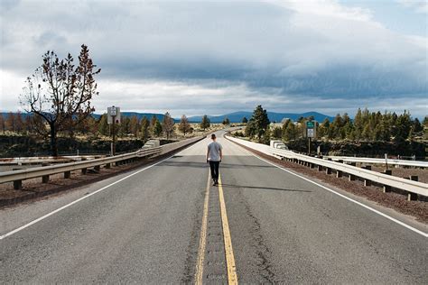 Single Young Man Standing In Middle Of Road During Travel By Stocksy