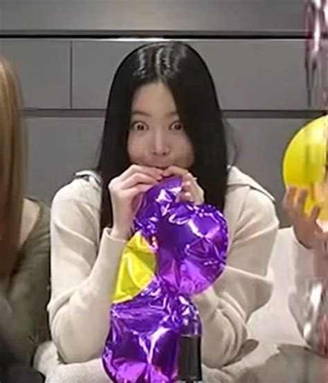 Two Women Sitting At A Table With Purple And Yellow Balloons In Front Of Their Faces