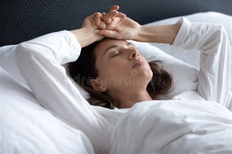 Stressed Young Brunette Woman Lying In Bed With Hands On Head Stock