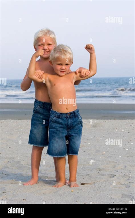 Two Young Boys Pose On Beach In Summer Flexing Muscles Stock Photo Alamy