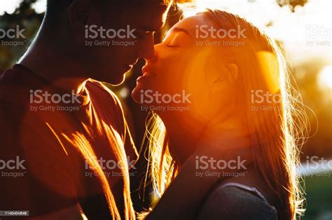 Close Up Portrait Of A Beautiful Young Caucasian Couple Kissing Against Sunset Light While
