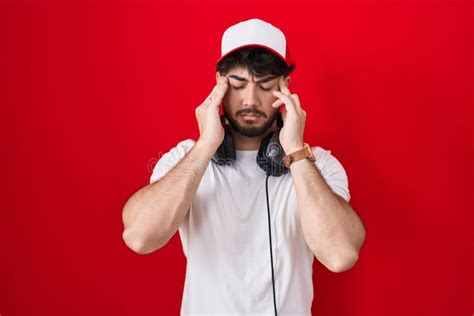Hispanic Man With Beard Wearing Gamer Hat And Headphones With Hand On