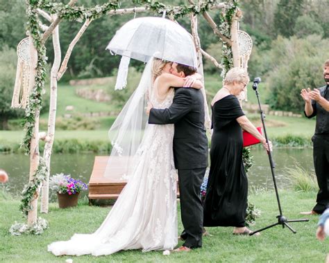 The Bride And Groom Kiss Under An Umbrella In The Rain Wildflower Wedding Montana Wildflowers