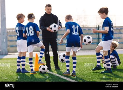 Young Coach Teaching Kids On Football Field Trainer Explains To