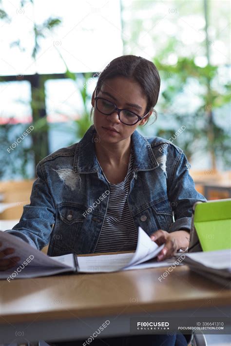 Female University Student Studying At Desk In Classroom — Reading Post