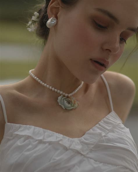 A Woman Wearing A White Dress And Pearl Necklace