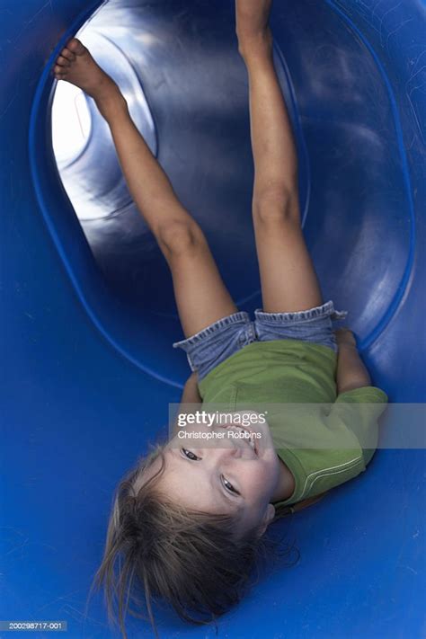 Girl Lying Upside Down In Tubular Slide Smiling Portrait High Res Stock
