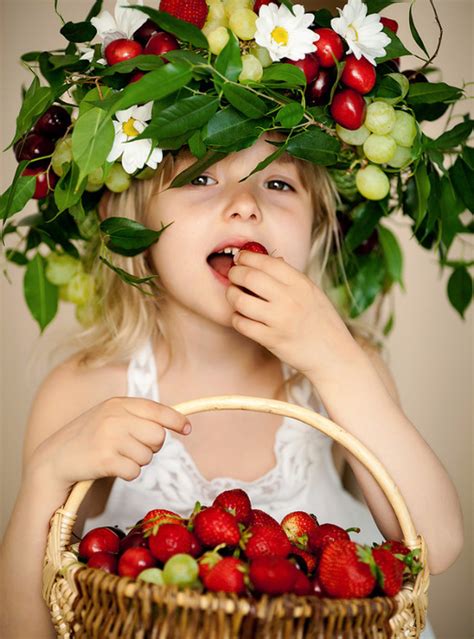 Фото Девочка с красивым венком на голове сделанный из ягод цветов и листьев держит в руке