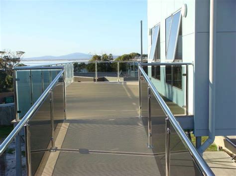 An Outdoor Walkway Leading To A Building With Glass Railings