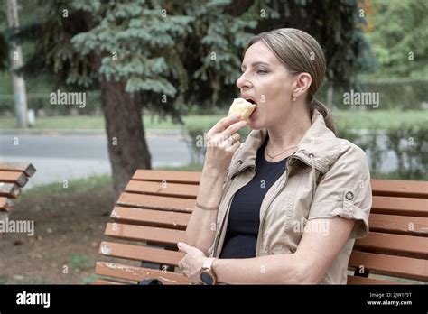 Woman Relaxing In Park She Sits On Bench Alone And Eats Ice Cream Stock Photo Alamy