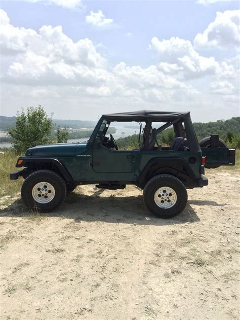 A Green Jeep Parked On Top Of A Dirt Field