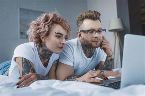 Premium Photo Young Tattooed Couple Using Laptop On Bed In Bedroom