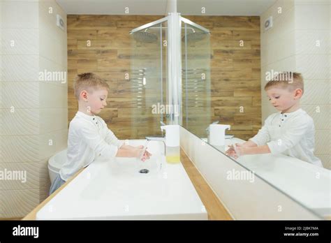 Little Boy Washes His Hands With Soap Disinfects In The Bathroom At