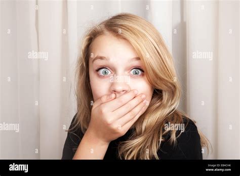 beautiful blond caucasian surprised girl opened her eyes wide and covers her mouth with her