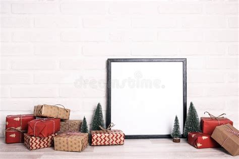 empty black frame with miniature christmas trees and heap of wrapped ts against white brick
