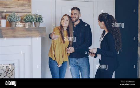Real Estate Agent Is Meeting Happy Married Couple Showing Papers And Telling Them About New