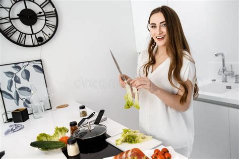 Young Beautiful Girl Is Preparing Breakfast In A Modern White Kitchen