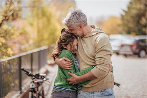 Teenage Daughter Hugging Her Father Outside In Town When Spending Time