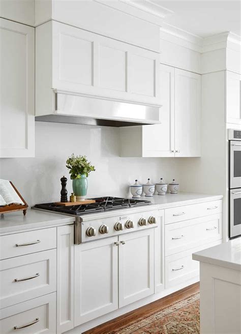 From the same picture, you can even get color inspirations for your shaker cabinets and the island paired with it. white wood hood metal band, modern white kitchen with breakfast table, built-in banquette, white ...