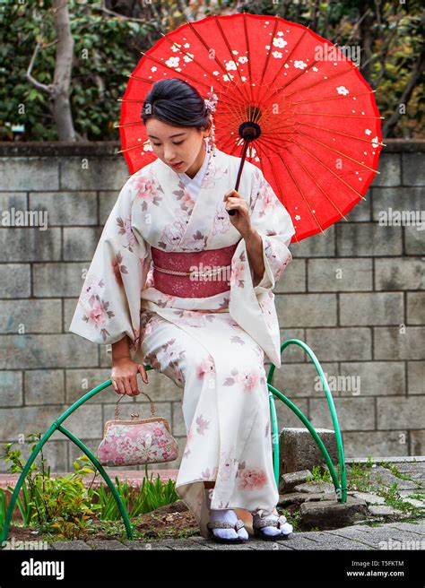 Beautiful Japanese Woman In White Kimono With Red Sash And Red Umbrella