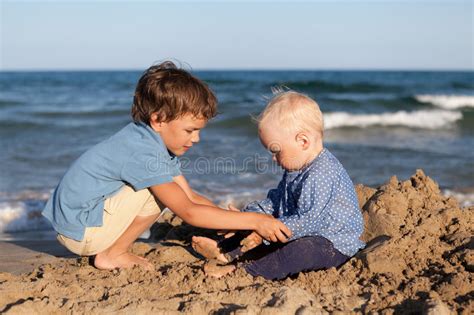 Brother And Sister Playing In Sand At Beach Stock