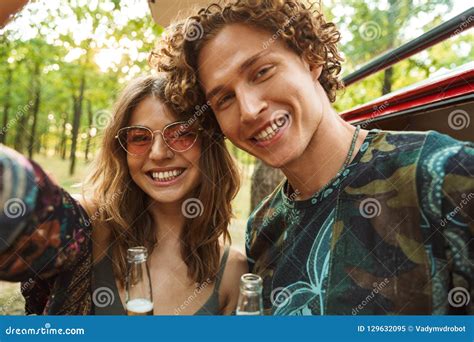 photo of beautiful hippie couple man and woman smiling and taking selfie in forest near retro