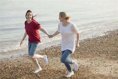 Playful Lesbian Couple Holding Hands And Running Photograph By Caia Image Science Photo Library