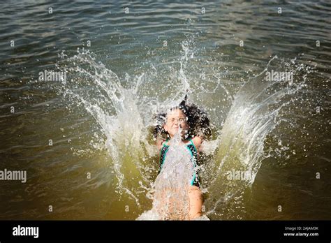 Jeune fille dans un maillot de bain sautant dans le lac faisant de grandes éclaboussures Photo