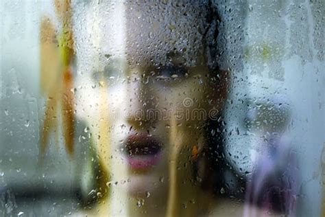 Beautiful Woman Behind The Glass With Water Drops Looking Directly At Camera Girl Takes A