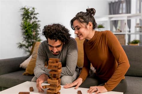 free photo husband and wife playing a wooden tower game