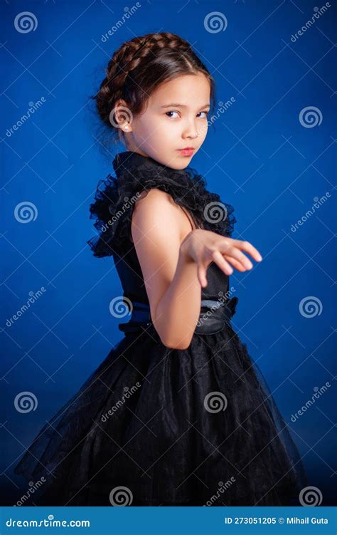 Little Girl In A Black Dress With A Pigtail Hairstyle On Her Head Poses
